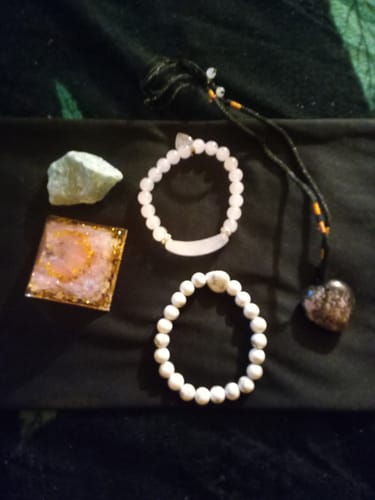 Customer's AuraBloom Subscription Box contents, including two beaded bracelets, a crystal, and a heart necklace.