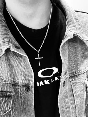 Cliente mostrando su Crucifix Pendant con cadena de cuerda sobre una camiseta negra.
