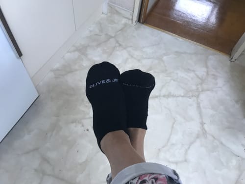 Reviewer's feet, crossed at the ankles, wearing the black Ankle Socks indoors on a marble-style floor.