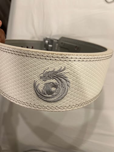 Customer's close-up of the white Dragonforged Lever Belt, highlighting the textured finish and embroidered dragon logo.