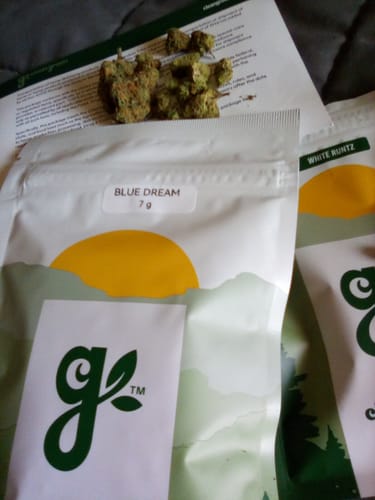 Customer's Blue Dream buds laid out in front of the 7g product pouch.