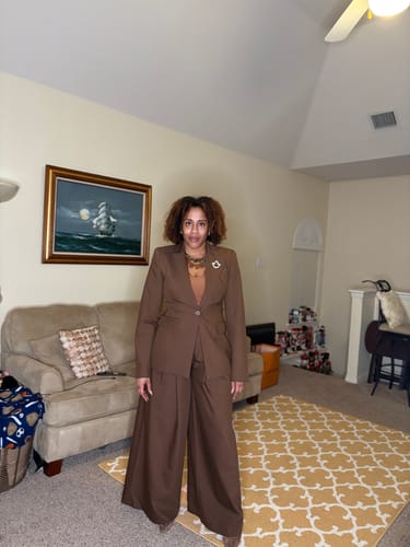 Customer wearing the brown Suiting Pleated Wide-Leg Pant and matching blazer in a living room.