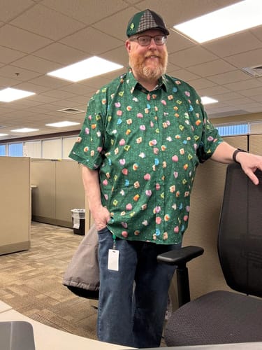 Customer wearing the green Lucky Charms 'Marshmallow Madness' short-sleeve shirt in an office setting.