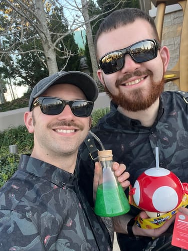 Two customers smiling for a photo outdoors in their matching 'Unleash the Fury' How to Train Your Dragon shirts.