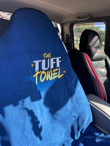 Customer's blue Tuff Towel seat cover draped over the driver's seat inside a car.