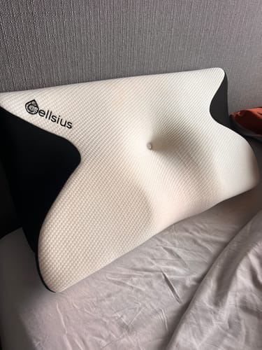 Avis d'un client : le coussin d'alignement cervical Cellsius profilé, blanc et noir, posé sur un lit.