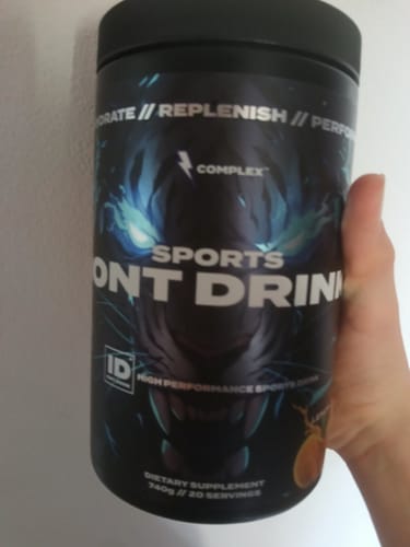 Reviewer's hand holding a large, black tub of the Sports Iont Drink.
