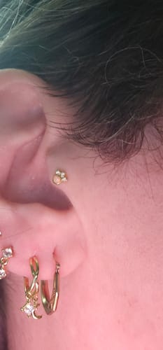 Close-up of a reviewer's ear, showing the Gaia Huggies Gold Pair with its moon and sparkle charm.