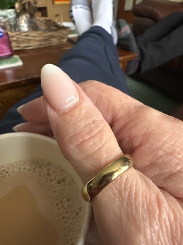 Customer's hand showing the loose fit of the gold Classic Stacking Ring on their thumb.