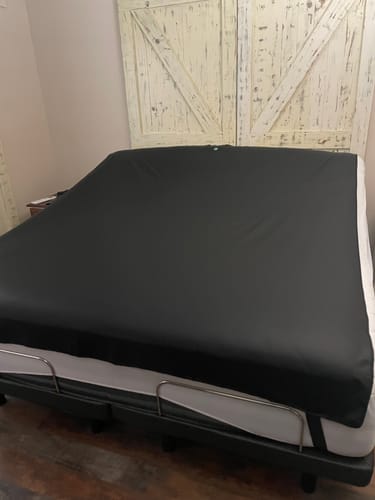 Customer's black Earthbound Grounding Mattress Pad fitted onto a king-sized adjustable bed in a bedroom.