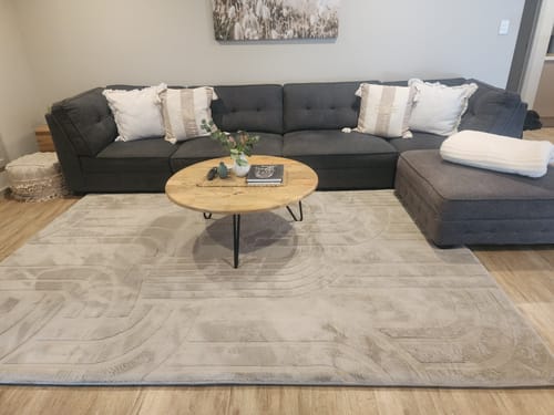 Customer's light-colored Mellow Mat with a carved pattern shown in their family room in front of a sofa.