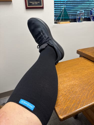 Customer wearing the black Performance Eucalyptus Compression Socks with their foot resting on a table.