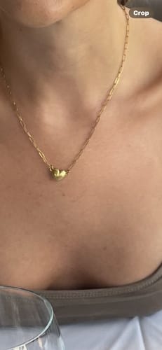 A reviewer wearing the gold Magnetic Love Necklace, showing the small heart pendant on its paperclip chain.