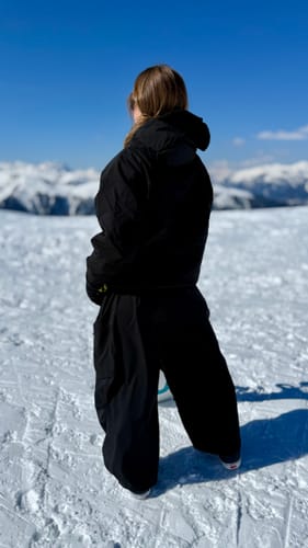 Reviewer from behind wearing black baggy snow pants on a snowy mountain.
