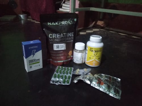 Reviewer's white bottle of YouWeFit Omega-3 Fish Oil placed on a floor with other fitness supplements.