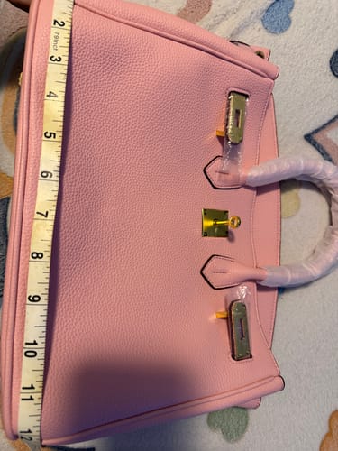 Customer measures the height of their pink, pebbled Warkin Bag with a tape measure.