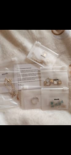Customer's five jewelry pieces from the clearance sale, displayed in their individual clear pouches on a soft surface.