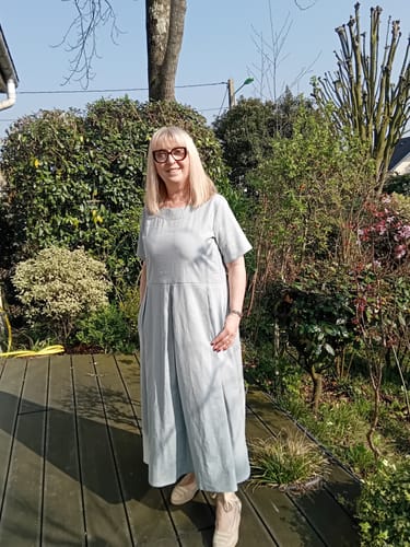 Cliente portant la Robe Louisa vert d'eau en extérieur. Elle se tient debout avec une main dans la poche de la robe.