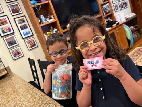 Reviewer's children smiling, one holding a large bag of colorful sweets including the Large Foam Raspberries.