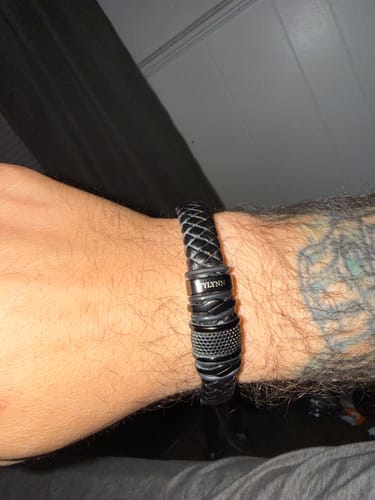 A customer's wrist with the personalized black braided bracelet, showing a close-up of the name on the clasp.