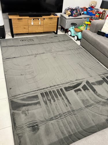 Customer's large Charcoal Mellow Mat laid out on a tiled floor in a living room.