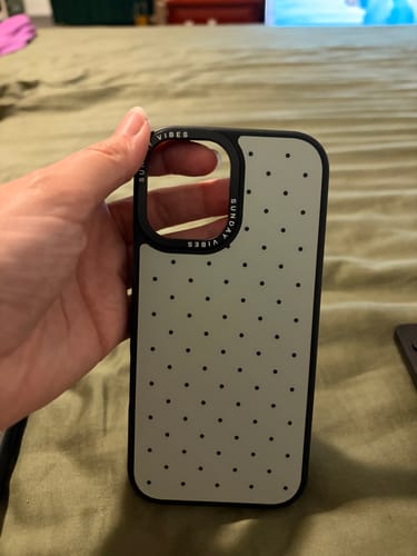 Customer holding a sage green iPhone case with black polka dots and a black bumper.