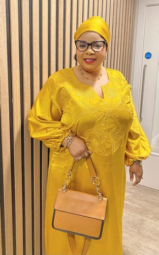 Reviewer wearing the gold Celine Clover Bracelet with a stylish yellow outfit and other jewelry.