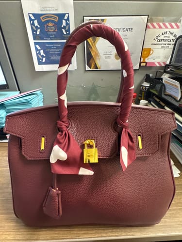 Customer's burgundy, pebbled Warkin Bag with a decorative scarf tied to the handle, sitting on an office desk.