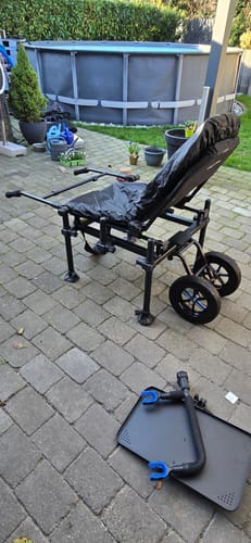 Recensent toont de gemonteerde Absolute 36 Feeder Chair Wheel Kit op een visstoel in een achtertuin.
