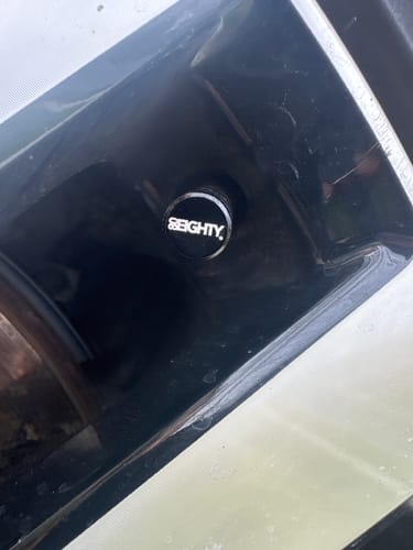 Close-up of a customer's black 80Eighty Valve Stem Cap installed on a car wheel.