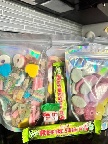 Reviewer's assorted candy haul in holographic bags, featuring the Strawberry Rings.