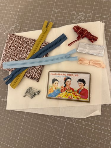 Customer's Haberdashery Starter Bundle laid out, showing the floral fabric, three colorful zips, and various trims.