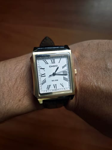 Cliente mostrando su Reloj Casio Tank con caja dorada y correa de cuero en la muñeca.