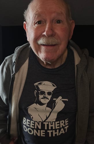 A happy reviewer wearing the dark grey 'Been There, Done That' tee under a zip-up hoodie.