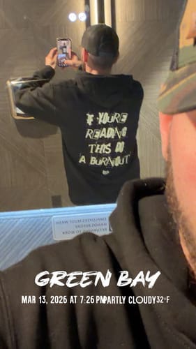 Reviewer taking a mirror selfie wearing the black Burnout Hoodie, showing the white text graphic on the back.