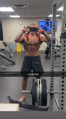 Customer showing a muscular, defined torso in a gym selfie while reviewing the testosterone support.