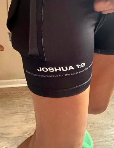 Close-up of a reviewer's Joshua 1:9 'Lion' Women's Performance Shorts, showing the Bible verse on the leg band.