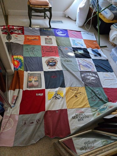 Customer's large Project Repat T-Shirt Quilt spread out on a floor, displaying a colorful grid of sentimental shirts.