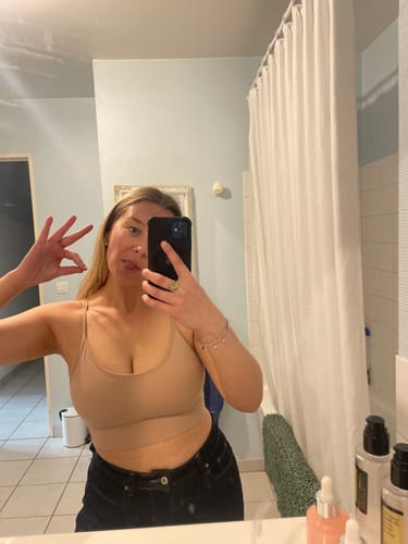 Cliente prenant un selfie dans un miroir, portant la brassière Everest beige dans une salle de bain.