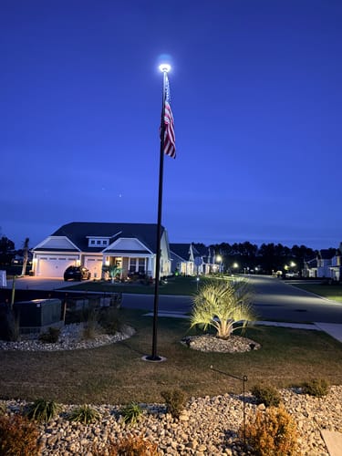 Reviewer's Ultra Heavy-Duty Home Flagpole with an American flag, shown illuminated at dusk by a top-mounted light.
