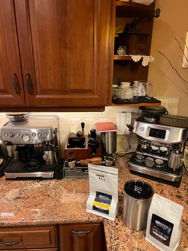 Customer's bags of Neapolitan Dark Roast Espresso Blend on a kitchen counter with two espresso machines.