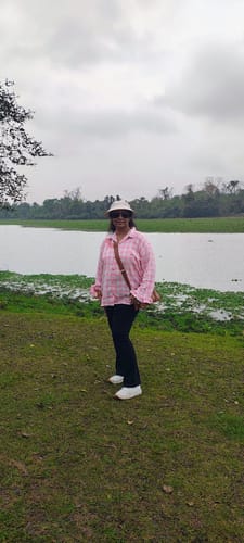Reviewer standing outdoors near a lake, wearing the stylish peach checked pure cotton top.