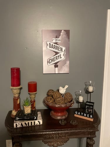 Customer's personalized street sign canvas with names 'Darren' and 'Cheryl' hanging on a wall over a decorated console table.