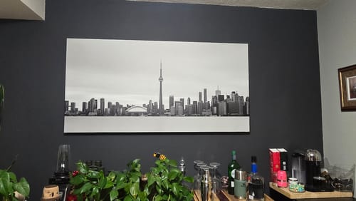 Customer's large 'Toronto Waterfront' Framed Canvas hanging on a dark gray wall above a home bar.