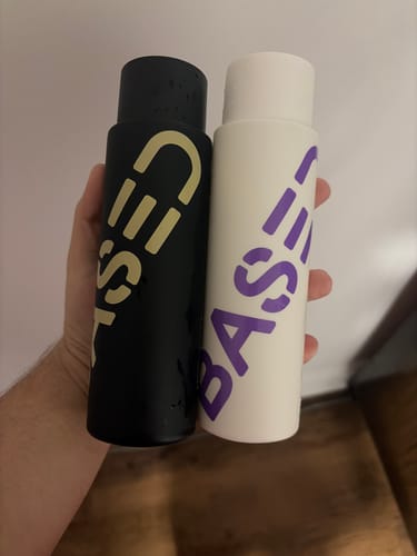 Reviewer holding the Shampoo in a black bottle and the Base conditioner in a white bottle.