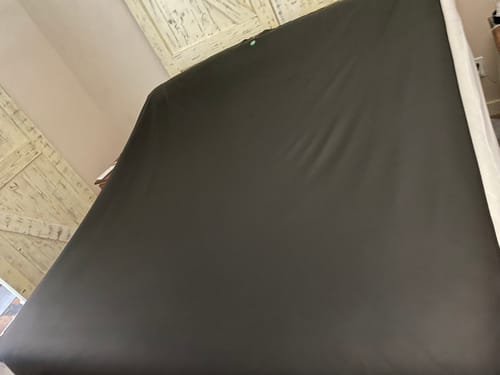 Close-up of the reviewer's black Earthbound Grounding Mattress Pad spread across a mattress.