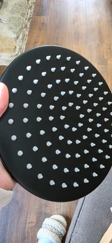 Customer holding the high-quality, black rain shower head from the dual shower head set.