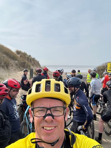 Reviewer wearing a Black Nasal Strip and yellow cycling helmet at a beach race.