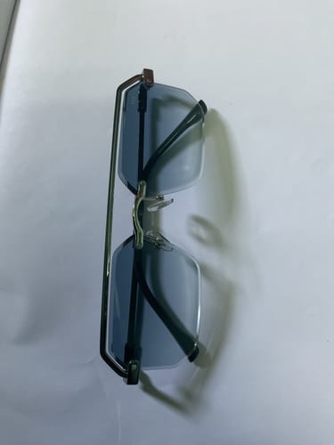 Reviewer's Allure Blue & Clear Half Rim Sunglasses folded on a white surface, showing the frame and lenses.
