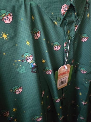 Customer's close-up of the green Lucky Charms shirt, showing the repeating pattern of Lucky the Leprechaun and yellow stars.